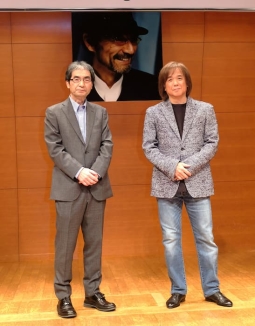 新井満さんの写真の前に立つ富澤一誠氏（左）、三浦和人（右）